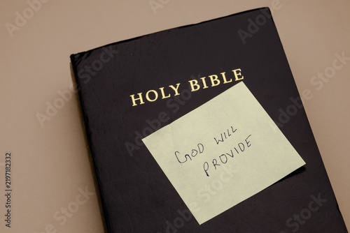 Foto A black holy book with a yellow sticky note featuring handwritten text of religi