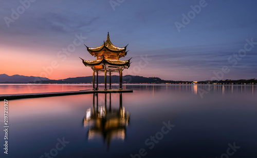 Картината върху платно Jixian Pavilion illuminated at sunset over calm water on West Lake in Hangzhou C