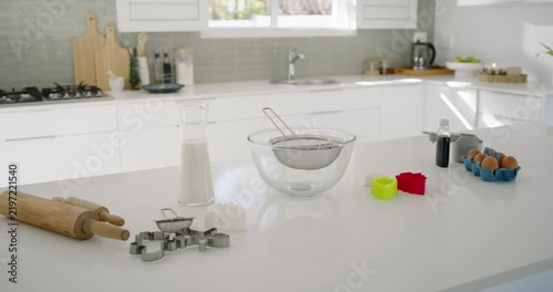 Camera is panning right, revealing clear mixing bowl with sieve and eggs, prepping cookies