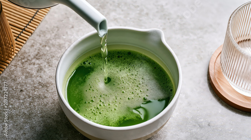 High angle view of green tea pouring into ceramic bowl with frothy surface