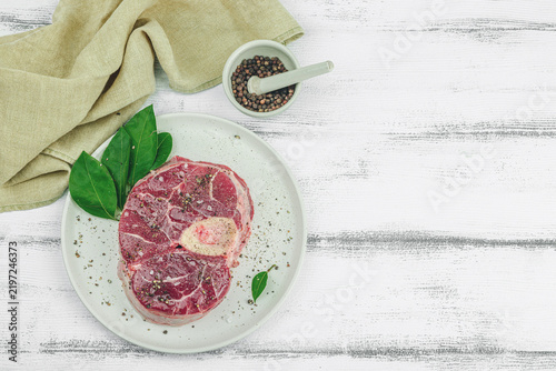 Raw ossobuco beef meat with spices and fresh herbs. Veal shank steak, traditional Italian ingredient