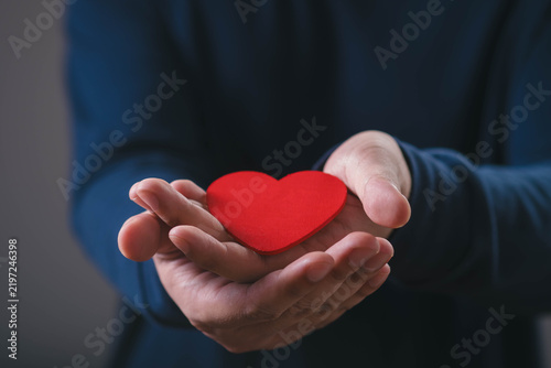 Hands holding a red heart symbolizing love, care, compassion, kindness, support, charity, donation, emotional connection, community, healthcare, social responsibility, and human connection.