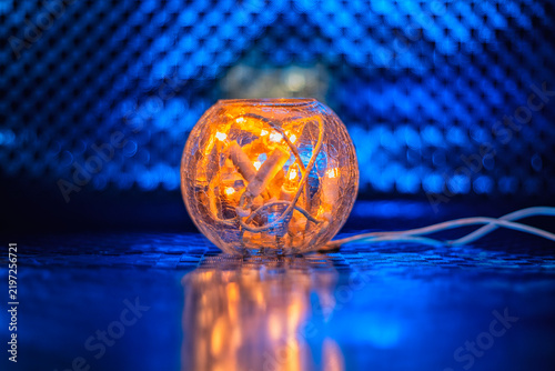 Glass lampshade with a garland of candles inside on a blue background