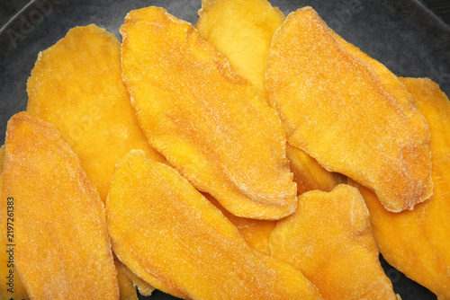 Slices of dried mango on black background. Macro photo