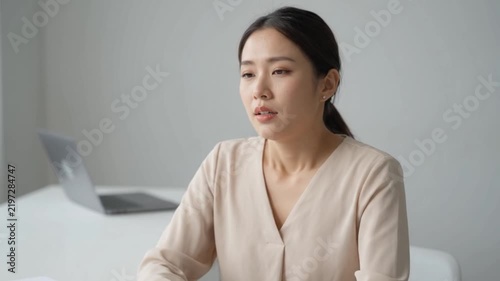 Young Asian Woman Experiencing Work Stress and Fatigue While Massaging Her Head in the Office