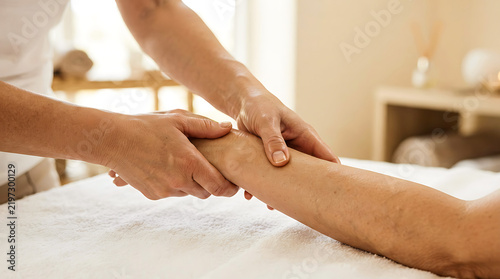 Professional therapist giving a relaxing arm and hand massage to a client in a bright wellness spa clinic