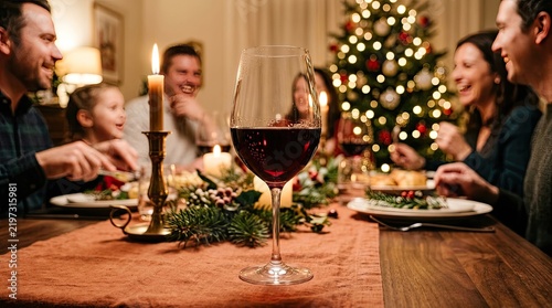 Red wine glass on a festive christmas dinner table with family members