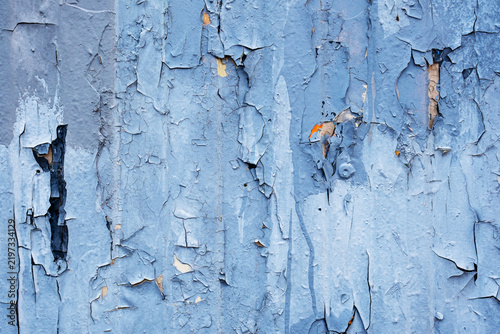 Weathered blue paint peeling and cracking on wooden wall surface, full frame texture