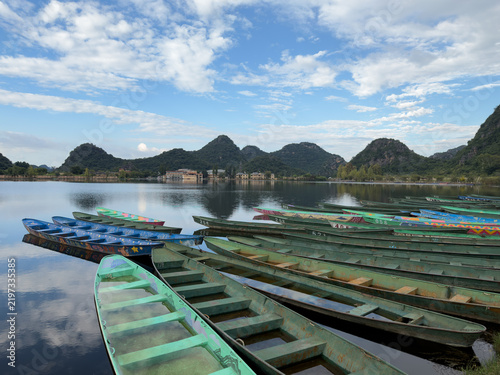 Fotografie Colorful wooden boats on Puzhehei Lake with karst mountains in Yunnan, China