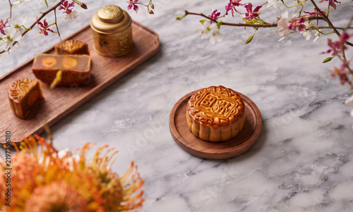Traditional Chinese mooncakes arrangement wooden trays marble tabletop blossoming branches floral decoration mid autumn festival pastry delicacy sweet dessert gourmet hospitality feast
