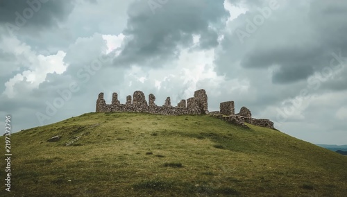 Old Stone Ruins Sit on a Grassy Hill Under a Cloudy Sky in the Countryside