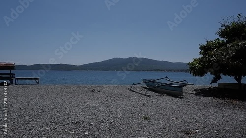 Rocky Beach with Traditional Outrigger Boats and Mountain View