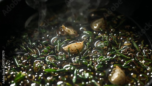 Cooking Herbs and Garlic in a Pot on the Stove While Steam Rises