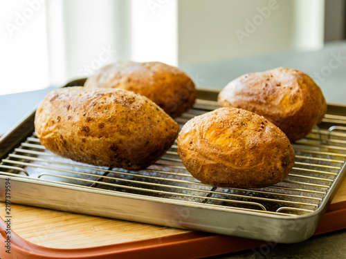 Whole Baked Potatoes on a Wire Cooling Rack in a Baking Pan Stock Photo