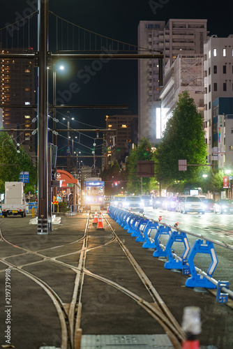 Fototapeta 夜の市街地に延びる路面電車の線路と車の流れ