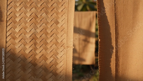 Natural medium wide composition of handcrafted bamboo texture beside woven heritage fabric with warm golden hour illumination highlighting detailed surface design