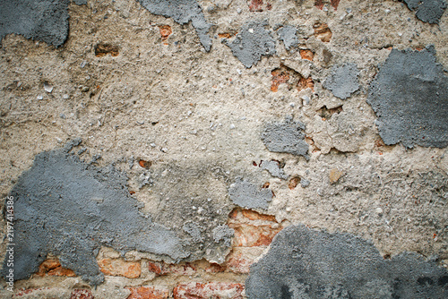 Foto Close up of an old weathered wall with damaged plaster, exposed red bricks, cement patches, and rough surface, representing deterioration, renovation, construction, aging, and grunge texture