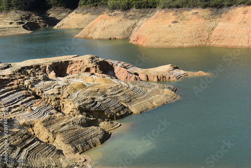 Fotografie Terraced erosion patterns on exposed reservoir bank at low water level, layered