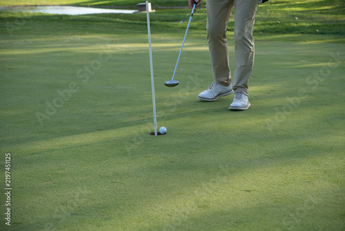 Cuadro en lienzo Golf ball resting at the lip of the hole beside the putter, close detail on the green - suspense and precision in putting