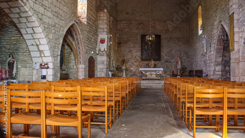 Фотография Intérieur de l'église de Penne, avec des murs en pierre brute et des arcs gothiques sous un éclairage tamisé, àl'ambiance calme et contemplative