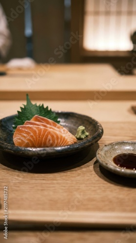 Salmon sashimi served in small ceramic bowl on Japanese restaurant counter