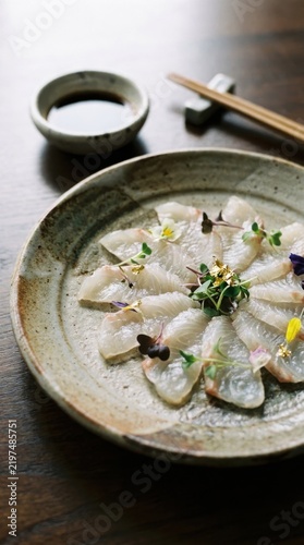 White fish sashimi presentation with microgreens on rustic ceramic plate