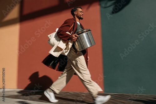 Southeast Asian man carrying a steel slow cooker for thanksgiving dinner, cheerful and hurried with motion blur and copy space