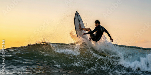 Male surfer performing a turn on a wave in the ocean during sunset with natural light