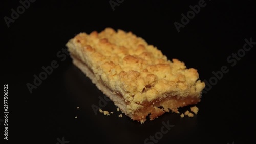 Close-up shot of a delicious slice of homemade apple crumble bar with fruit filling on a dark background. Perfect stock footage for bakery ads, dessert menus, and culinary concepts.