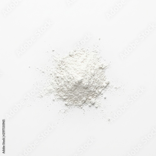 White powder scattered across a clean white surface with generous copy space in a minimalist overhead flat lay composition