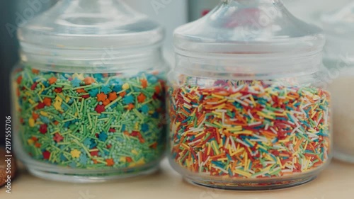 Colorful sprinkles in jars at a bakery store in the afternoon