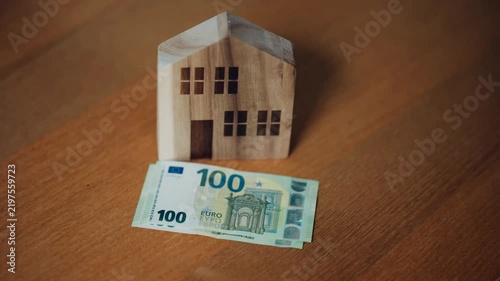Wooden house model with 100 euro banknote on wooden table, real estate investment concept