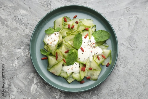 Obraz na płótnie Tasty salad with cucumber slices, goji berries and mint served on grey table, to
