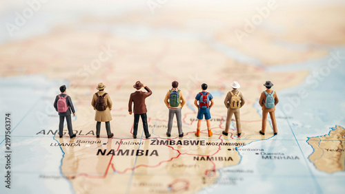 Group of diverse travelers standing on a map in Namibia with backpacks and casual clothing