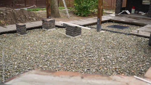 Unfinished patio or garden area during renovation. Shows installation of crushed stone, foundation work for pergola, and new walkways. Home improvement and DIY landscaping concept