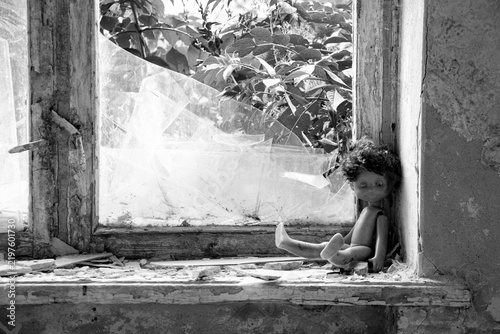 Принти на полотні An abandoned child's doll sits by a broken window in an abandoned house