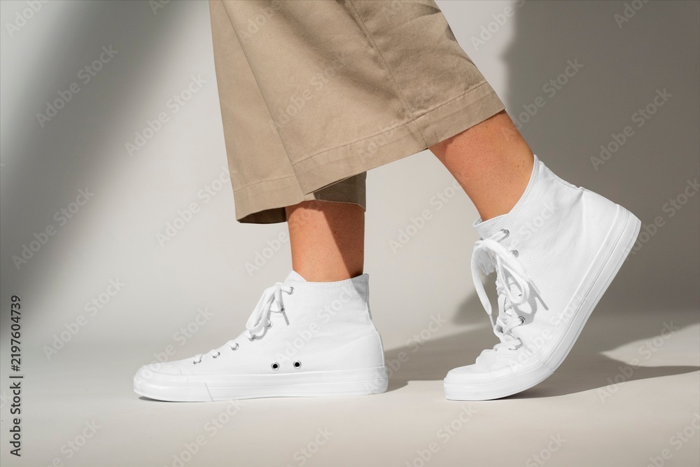 Obraz premium White high top sneakers with beige pants on neutral background