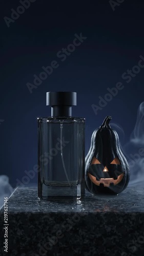 Perfume bottle and black pumpkin with carved face surrounded by drifting smoke in a dark studio, Halloween fragrance product display Vertical video