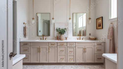 Elegant double vanity bathroom with gold accents, light cabinets, and mirrors, creating a bright, functional space for homeowners.