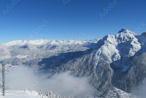 Snow covered mountain panorama, with a snow covered forest and snow covered valley in winter. Taken in Tirol, Austria. 