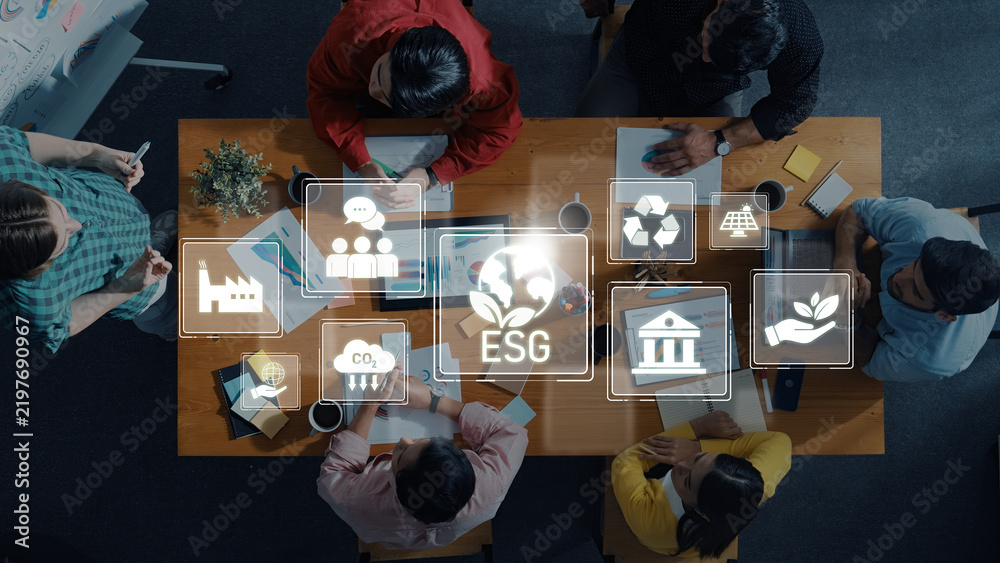 Obraz premium A diverse group of professionals engages in a strategic meeting focused on ESG concepts, with digital icons highlighting key areas like sustainability and governance. Trope