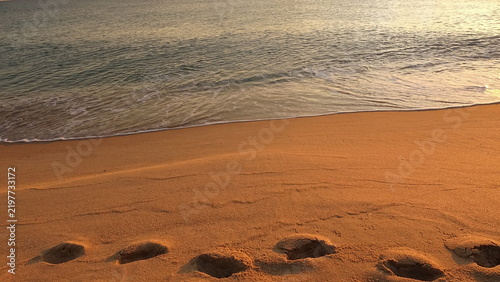 Foto Peaceful view with footprint trails on the sandy shoreline