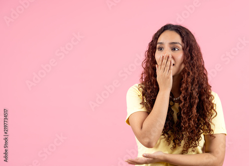 Quadro su tela Young woman covering mouth feeling surprised