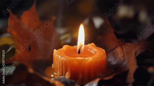 Cozy Autumn Candlelight A Warm, Glowing Orange Candle Surrounded by Crisp Fall Leaves