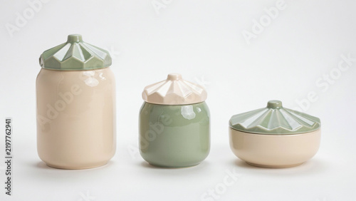 Three ceramic jars with geometric lids in pastel green and beige on a white background
