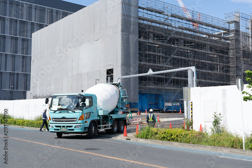 建設現場から道路へ出るコンクリートミキサー車と誘導する交通誘導員