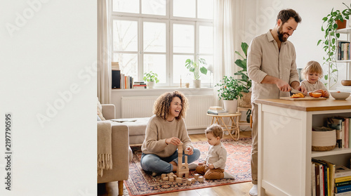 Happy family with children playing blocks and cooking together in bright modern living room and kitchen at home