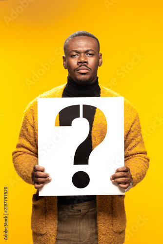 Foto Portrait of a contemplative man holding a large question mark sign against a vib