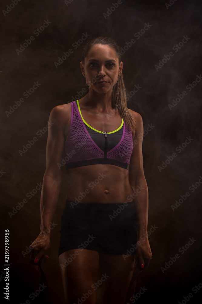 Obraz premium Fitness enthusiast in athletic attire performing exercise with focused expression in atmospheric lighting