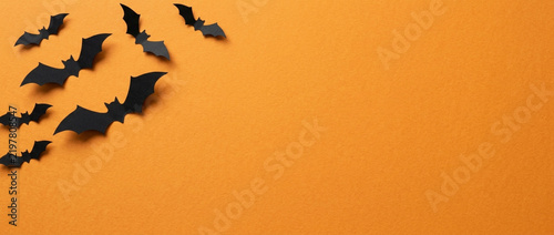 Black paper bats flying on an orange background - Halloween theme